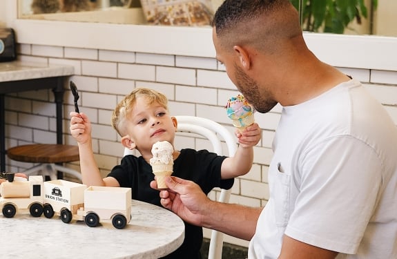 Child sharing ice cream cone with dad