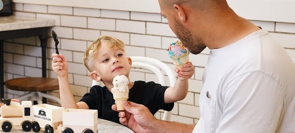 Child sharing ice cream cone with dad