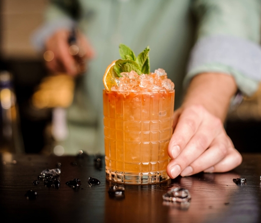 A cocktail with garnish being presented at the bar at Death & Co Denver in Denver,